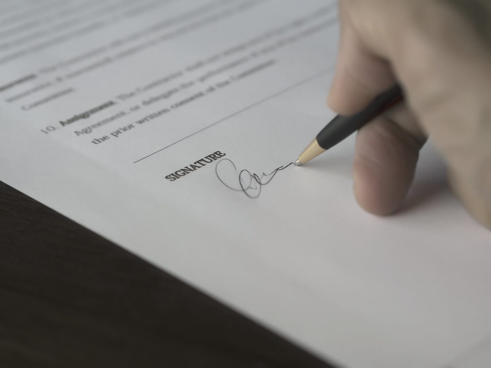 A contract being signed by hand at a desk